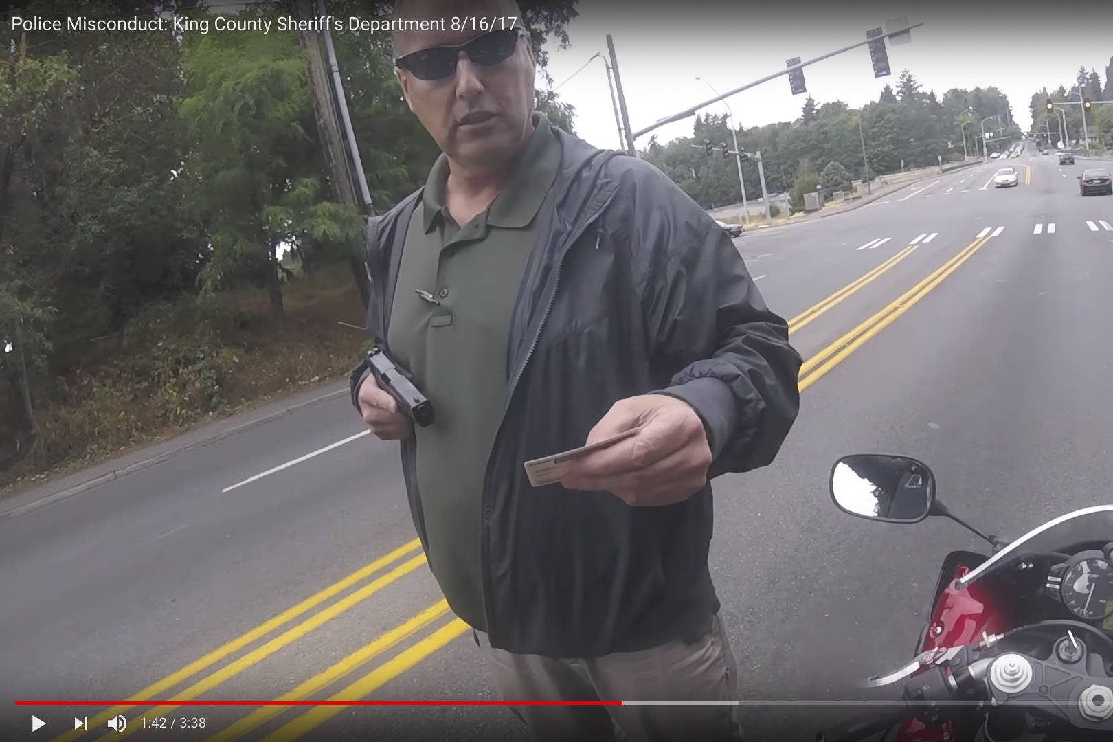 An unidentified gunman, later revealed to be a King County detective, sticks up a motorcyclist at gunpoint. Screenshot via YouTube user Squid Tips, aka Alex Randall