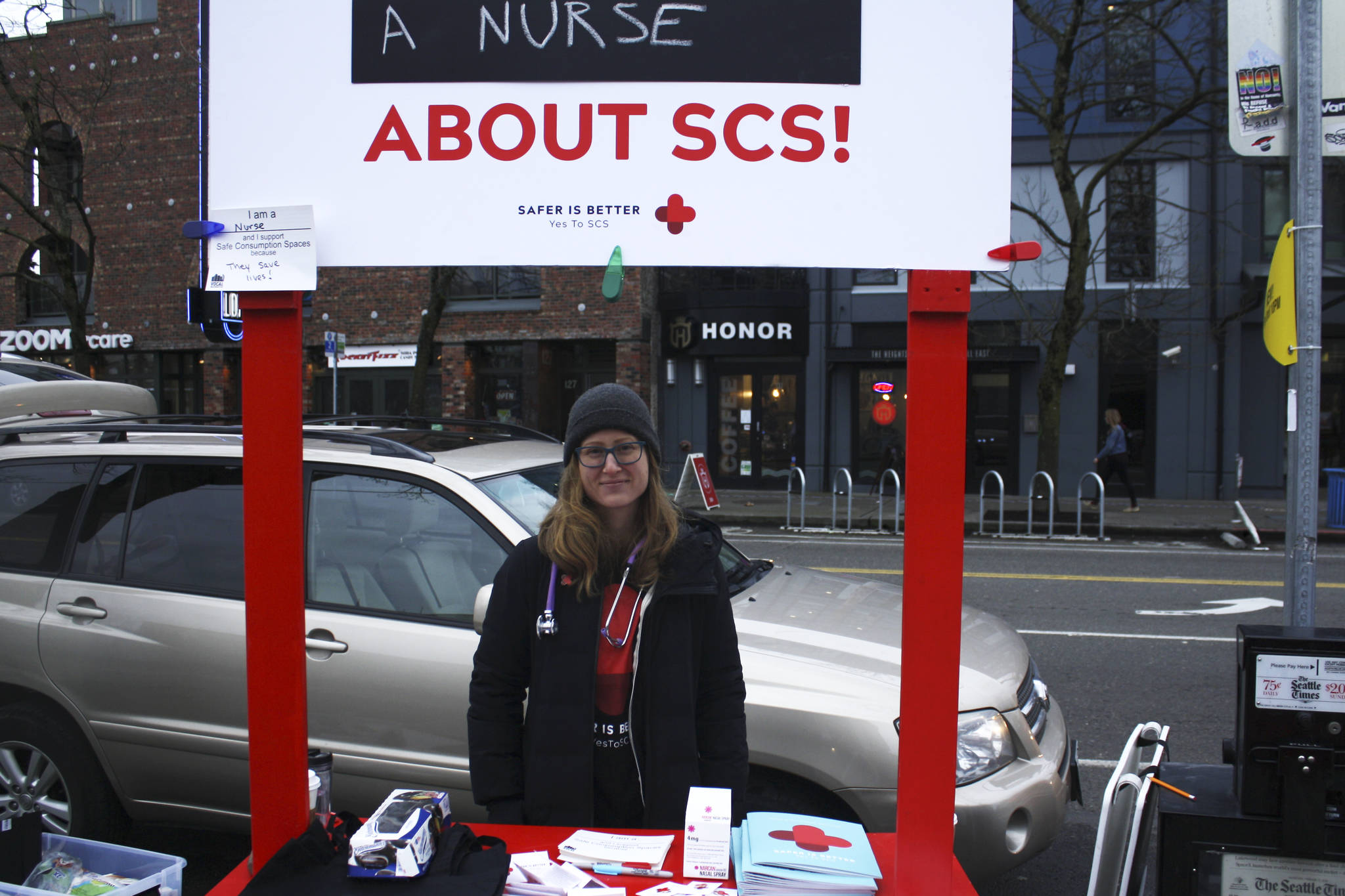 Mandy Sladky, a registered nurse, answers questions about safe consumption spaces at a public information booth outside of the Capitol Hill light rail station on February 7, 2018. Photo by Melissa Hellmann