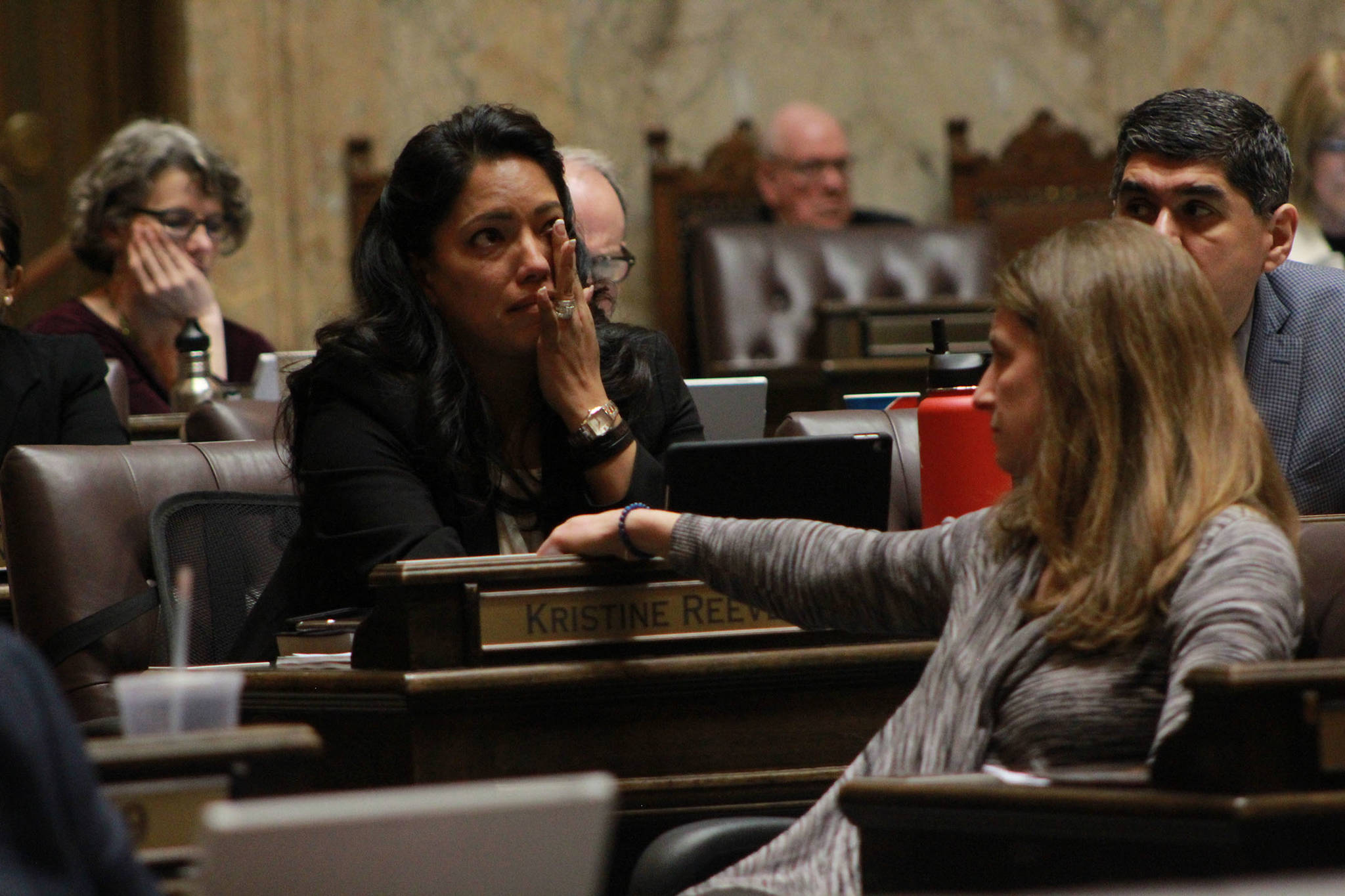 Rep. Kristine Reeves (D-Federal Way) battled tears during the House floor debate on a bill to ban bump stocks, while her colleague Rep. Tana Senn (D- Mercer Island) turned to comfort her. Photo by Taylor McAvoy