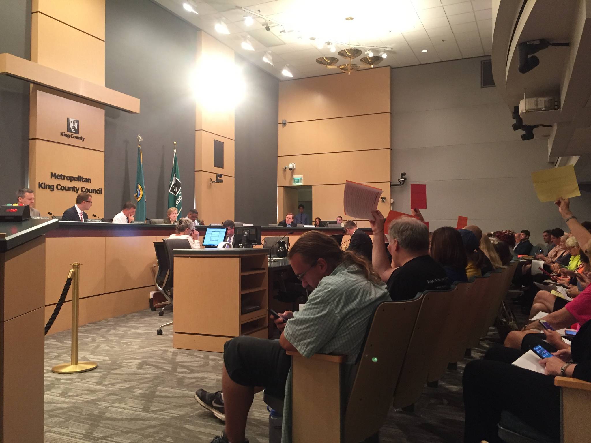 Members of the public held signs reading “homes over homeruns” and “#teamhousing” at the King County Council’s July 20 hearing. Photo by Josh Kelety