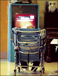 A patient in Western State's geriatric unit wheels himself around a dayroom in a "Broda" chair.