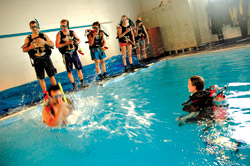 Top: Scuba instructor Anita Sederstrom urges students to jump in. Bottom: Tyler Stone helps Ruan Breedt gear up.
