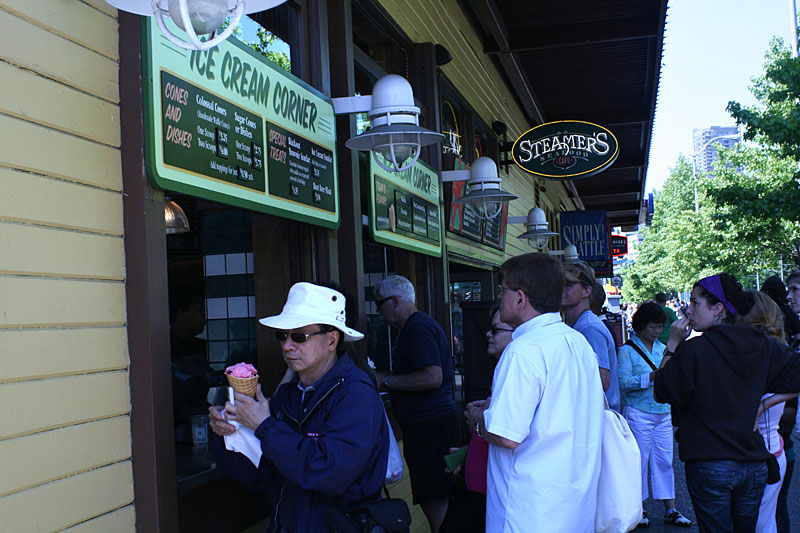 1)Tourists with ice cream: A group of tourists wait in line to buy ice cream from the Ice Cream Corner on Alaskan Way as they enjoy the sunshine by the piers.