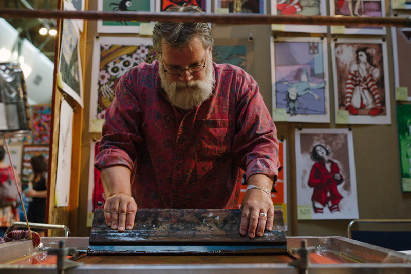 An artist creates a one of a kind Screen Print at Flatstock.