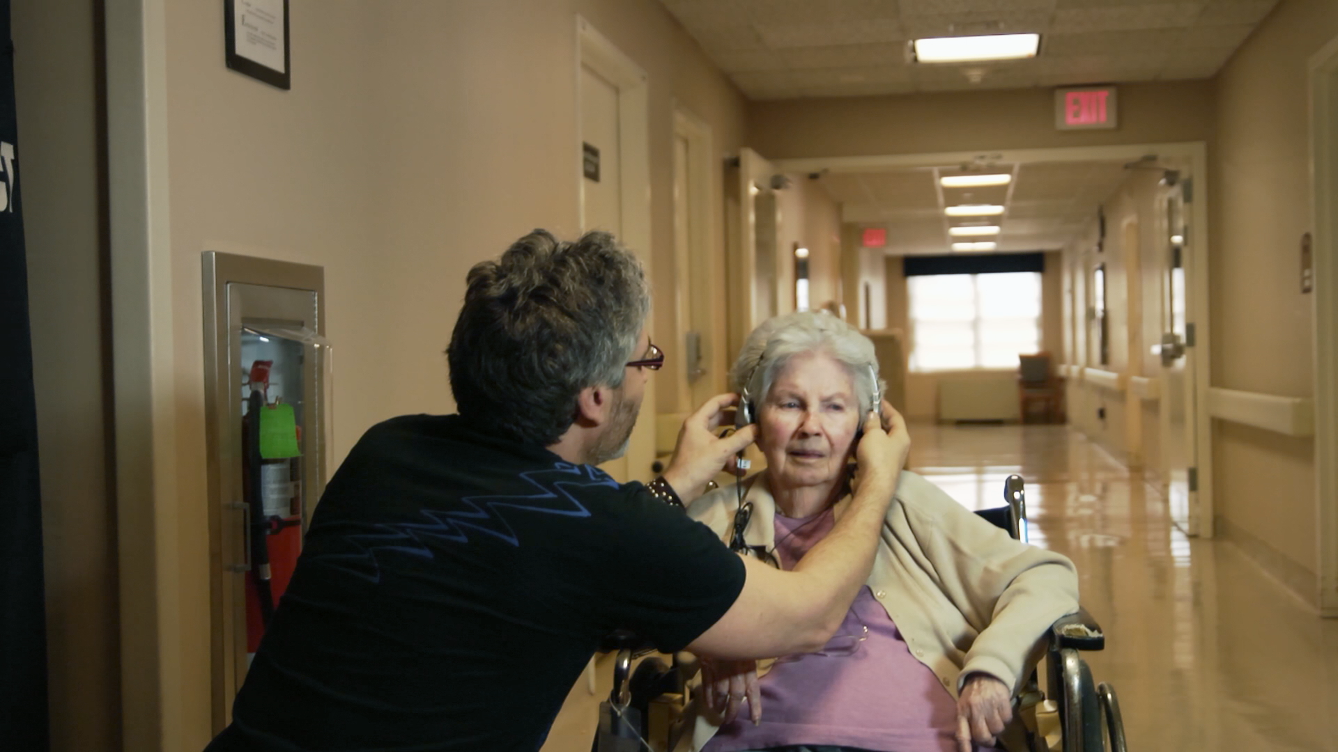 Director Rossato-Bennett helps a patient with her earphones.BOND/360/aliveinside.us