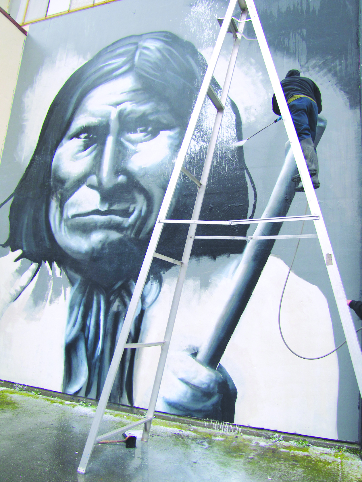 Geronimo stands strong as a worker scrubs away the vandal’s work.