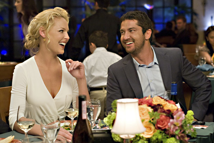 Heigl discovers where Butler’s hand went beneath the table.