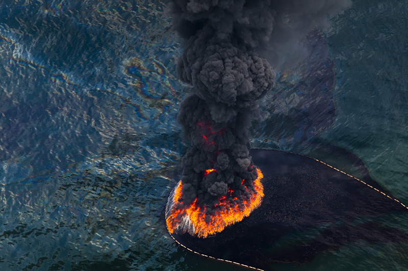 A plume of smoke rises from a burn of collected oil that was spilled from BP's Deepwater Horizon wellhead June 17, 2010. Photo © Daniel Beltra for Greenpeace.