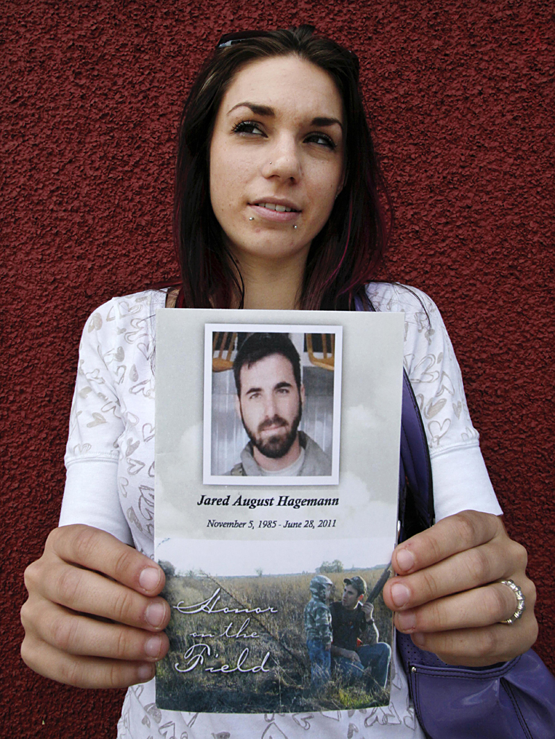 Ashley holds the memorial flyer from  the funeral service for her husband Jared.