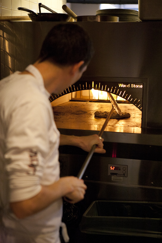 Cook Zack Chamberlain plucking a hot pita from the oven.