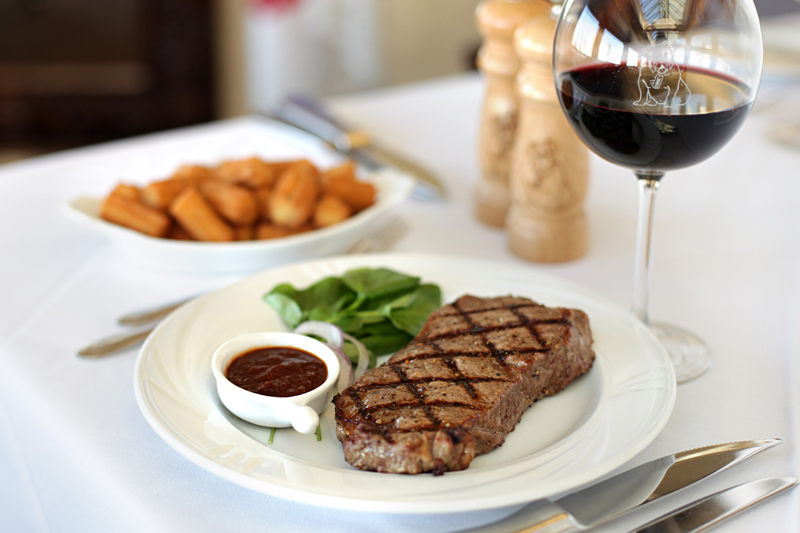 New York steak with truffled tater tots and glass of cabernet sauvignon