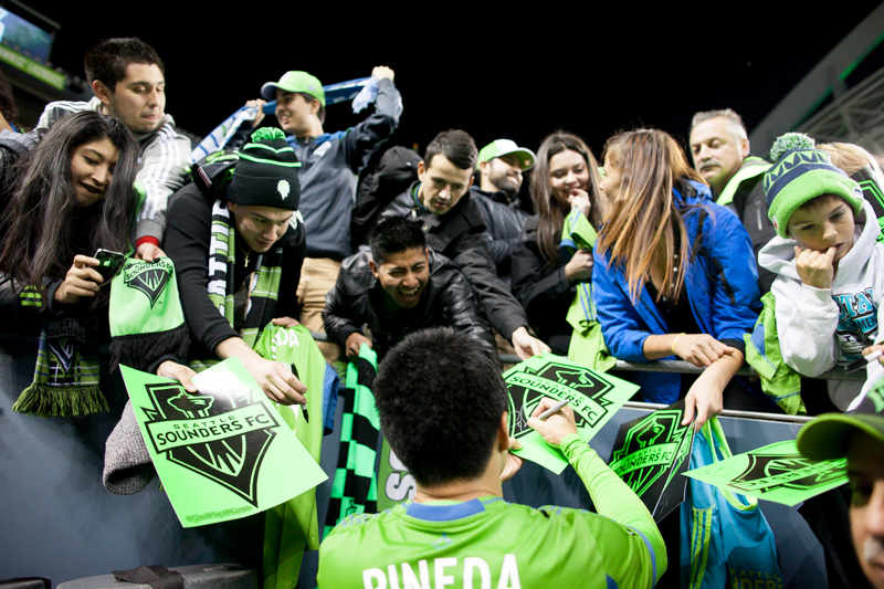 Seattle midfielder Gonzalo Pineda signs autographs for fans after the match.