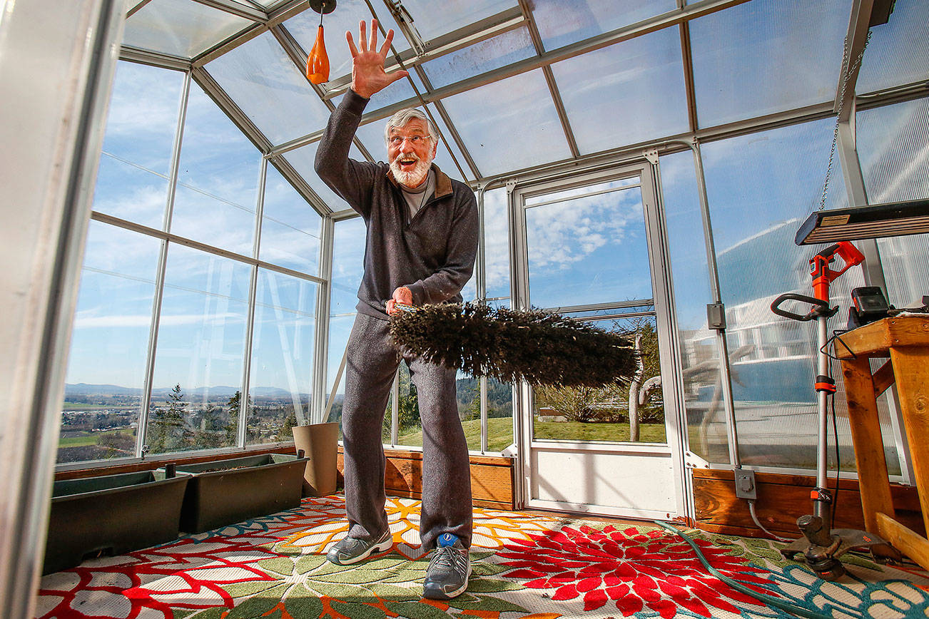 Holding a broom, Graham Kerr explains Monday how he saved a bird that had become trapped in his greenhouse. He plans to tell the story at the YMCA prayer breakfast April 19. (Dan Bates / The Herald)
