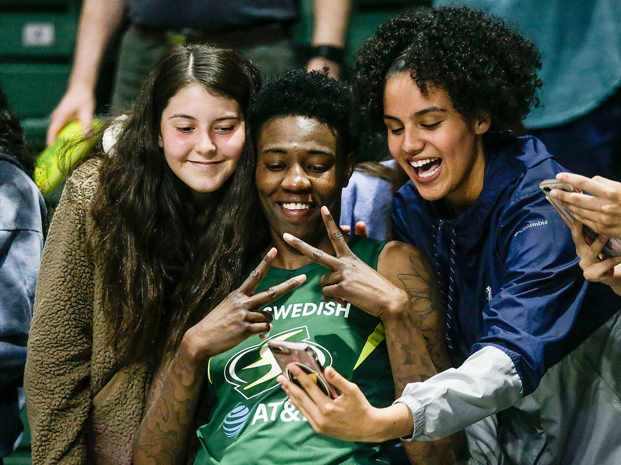 The Storm’s Natasha Howard poses for photos with fans after Seattle beat the Minnesota Lynx 84-77 on June 4 at the Angel of the Winds Arena in Everett. (Andy Bronson / The Herald)