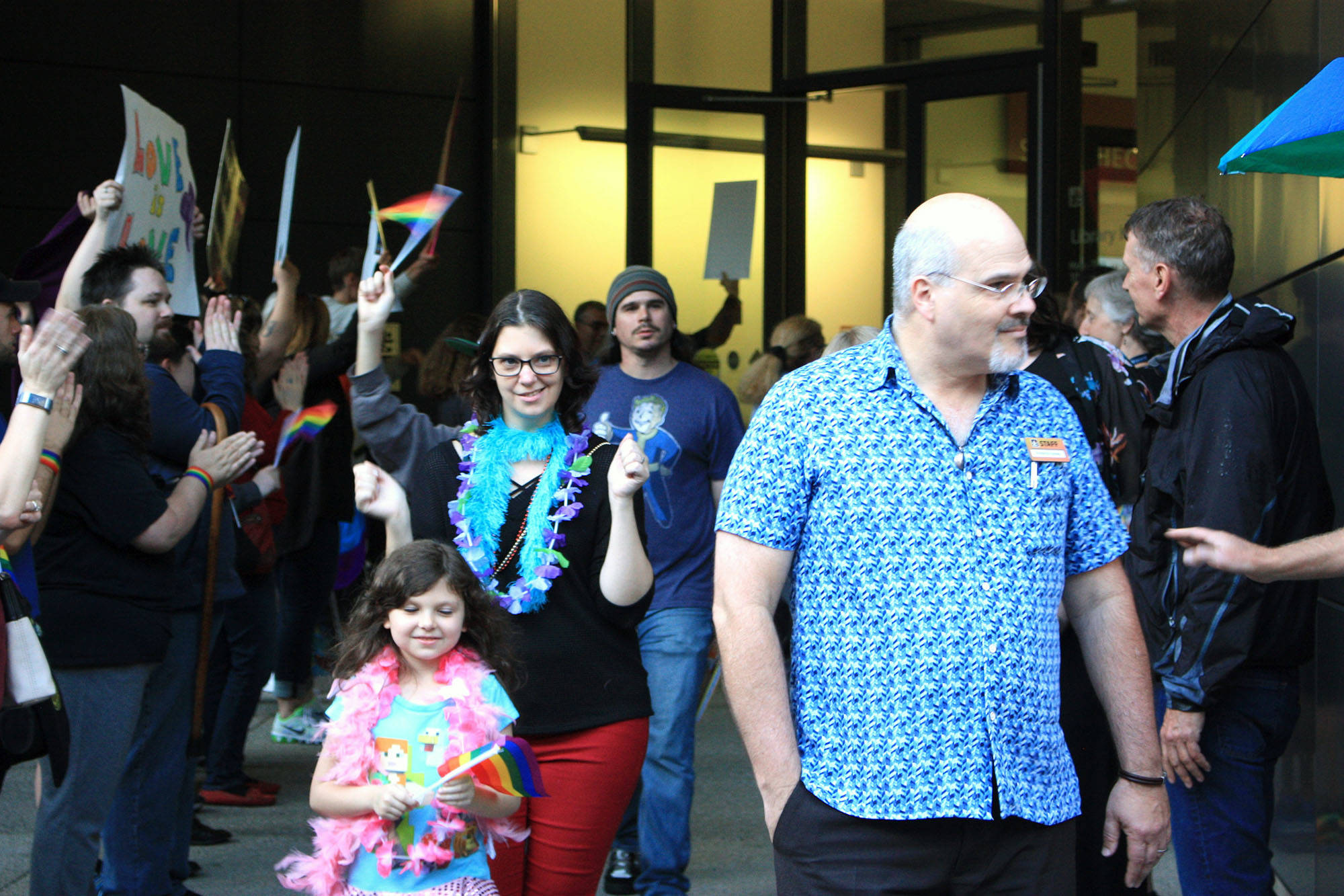 Attendees of the Drag Queen Story Hour at the Fairwood Library exit the event. A walkway was held open for them by supporters while protesters held signs condemning the event behind them. Aaron Kunkler/staff photo