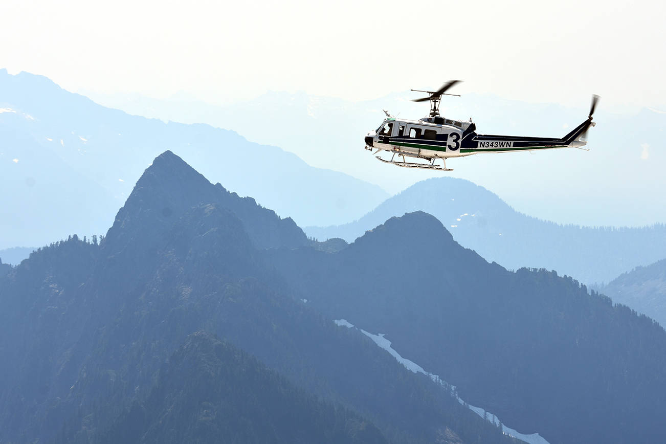 A helicopter crew scours rough terrain Sunday, Aug. 5, 2018, at Vesper Peak, in the search for missing hiker Sam Sayers, of Seattle. She went missing days earlier on the hike about 30 miles east of Granite Falls. (Caleb Hutton / The Herald)