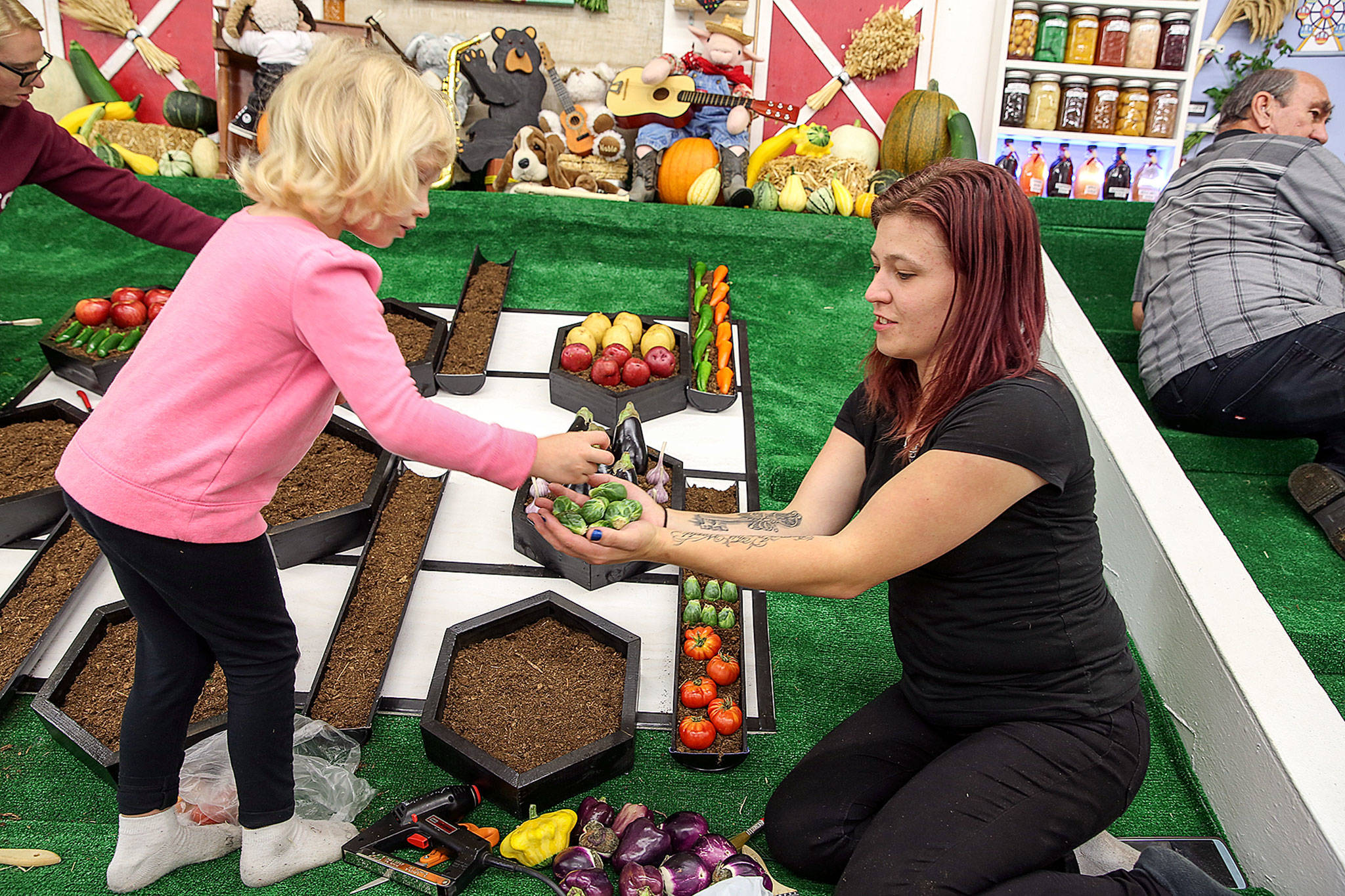Zoe Hart handles off vegetables to her mom Nicole Hart Wednesday afternoon at the Evergreen State Fairgrounds in Monroe. (Kevin Clark / The Herald)