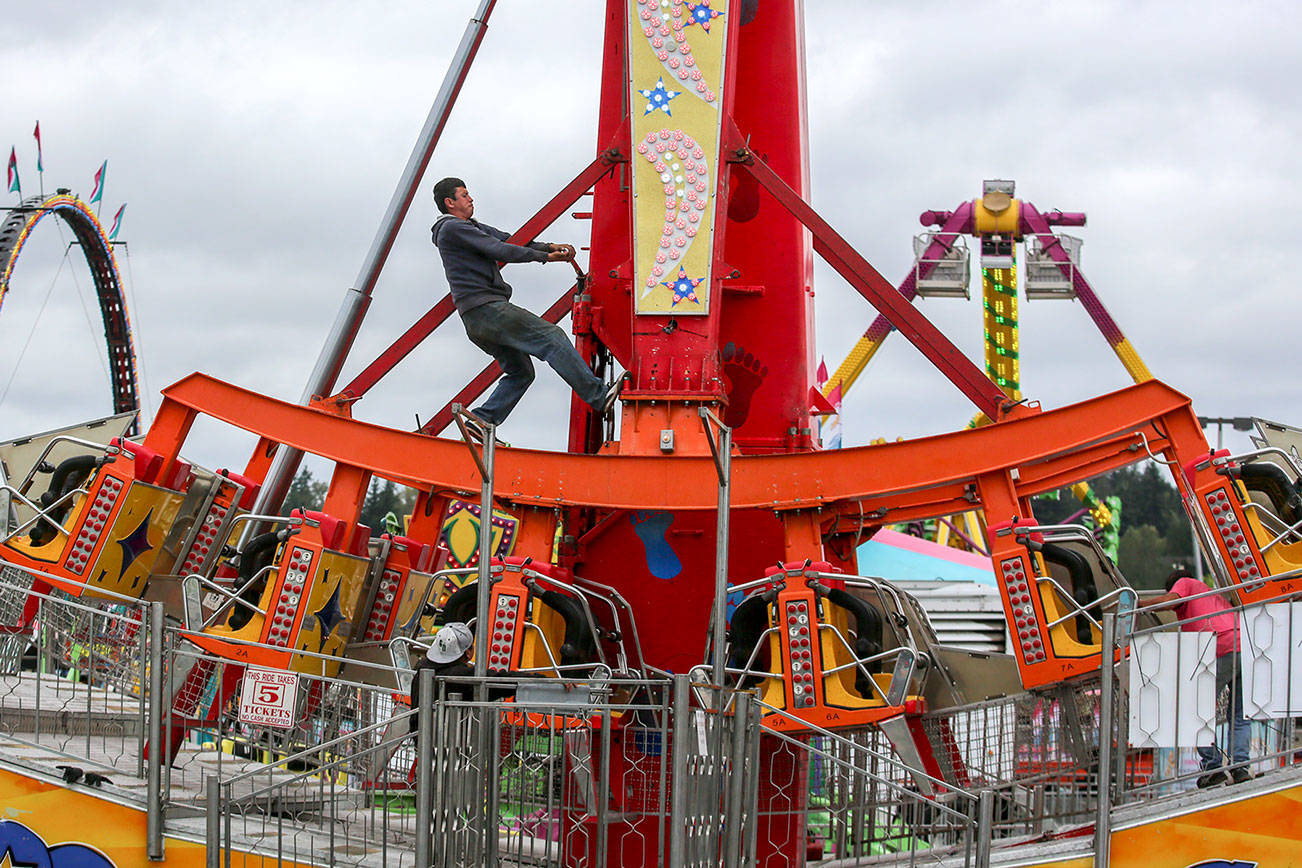 A crew member works to setup a ride Wednesday afternoon at the Evergreen State Fairgrounds in Monroe. (Kevin Clark / The Herald)