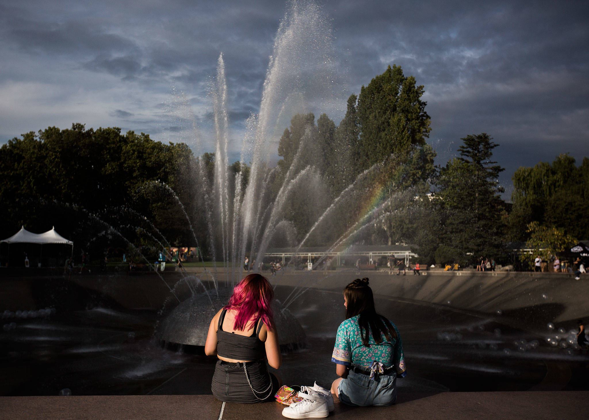 Two girls sit near the Seattle Center fountain to change shoes during Bumbershoot Music & Arts Festival on Friday, Aug. 30, 2019 in Seattle, Wash. (Olivia Vanni / The Herald)
