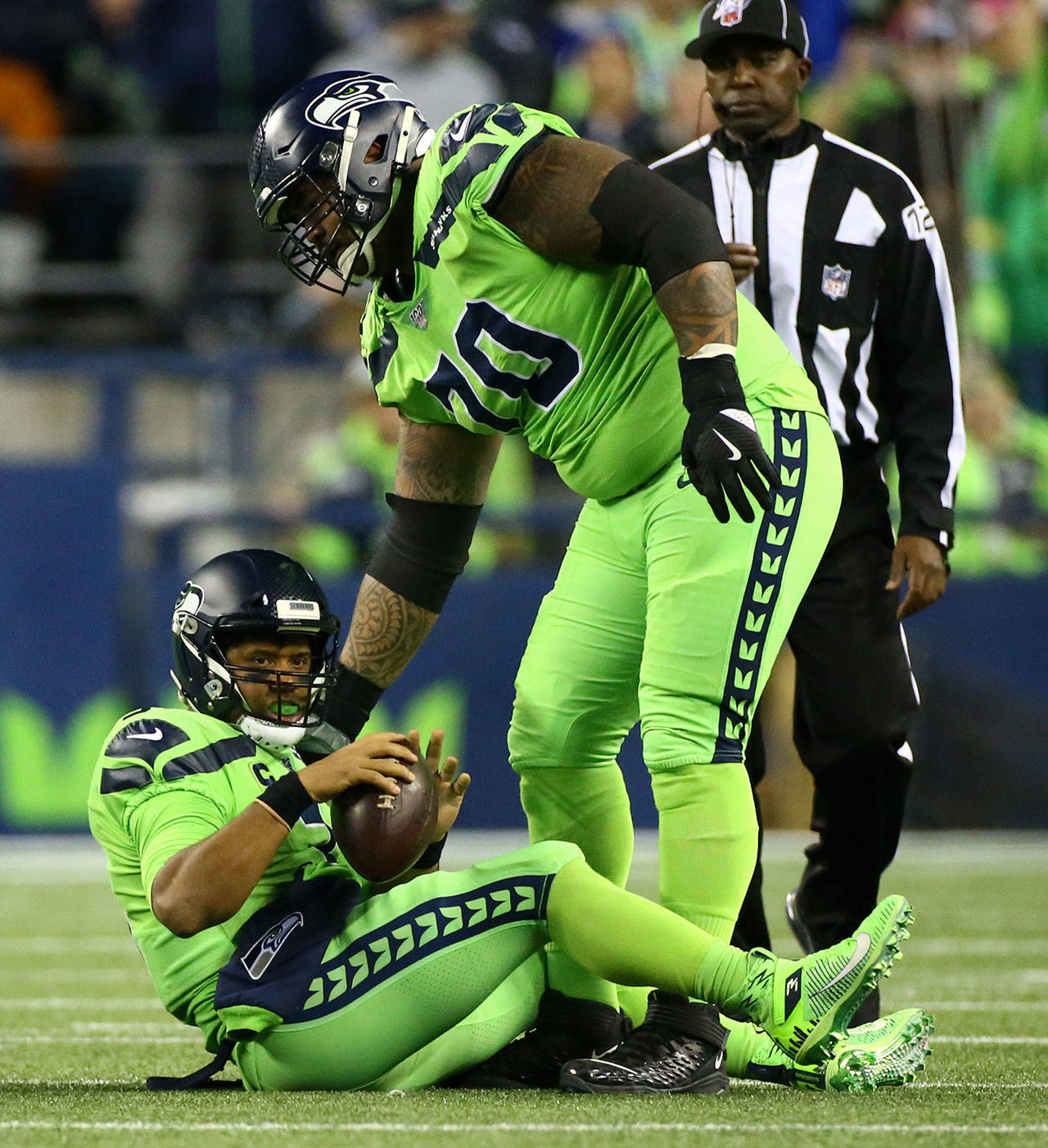 Seattle’s Mike Iupati helps Seahawks Russell Wilson to his feet after a tackle in the backfield during the Seahawks 30-29 win over the L.A. Rams on Thursday at CenturyLink Field in Seattle. (Kevin Clark / The Herald)