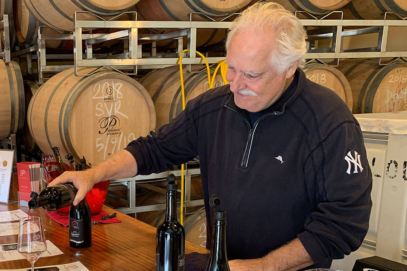 In this September 2019 photo, George Kirkish, owner and founder of Palouse Winery on Vashon-Maury Island, pours a glass of wine for Lori Coots during tasting room hours. (Kevin Opsahl/Sound Publishing)