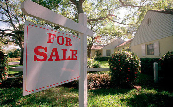 For sale sign hanging in front of house