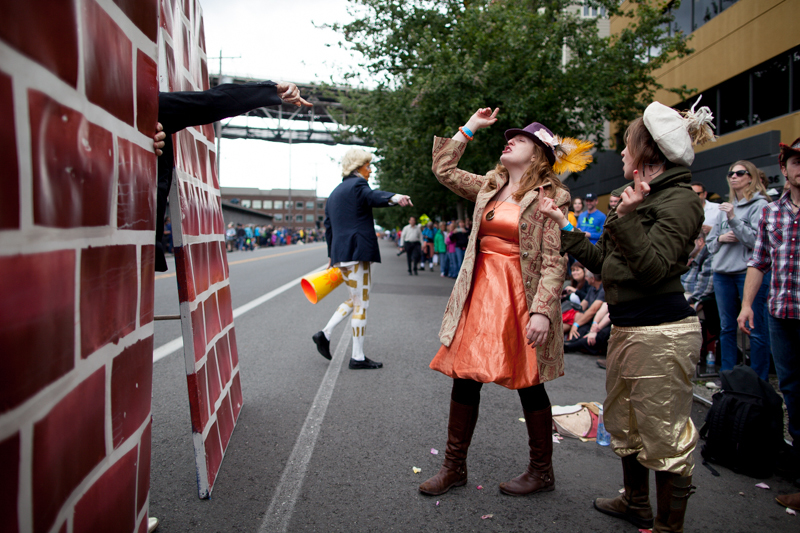 Onlookers have a fake argument with Trump impersonators and their giant brick wall.