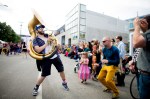 Susaphone player Logan Pendergrass with the Ten Man Brass Band dances along with a man in the street.