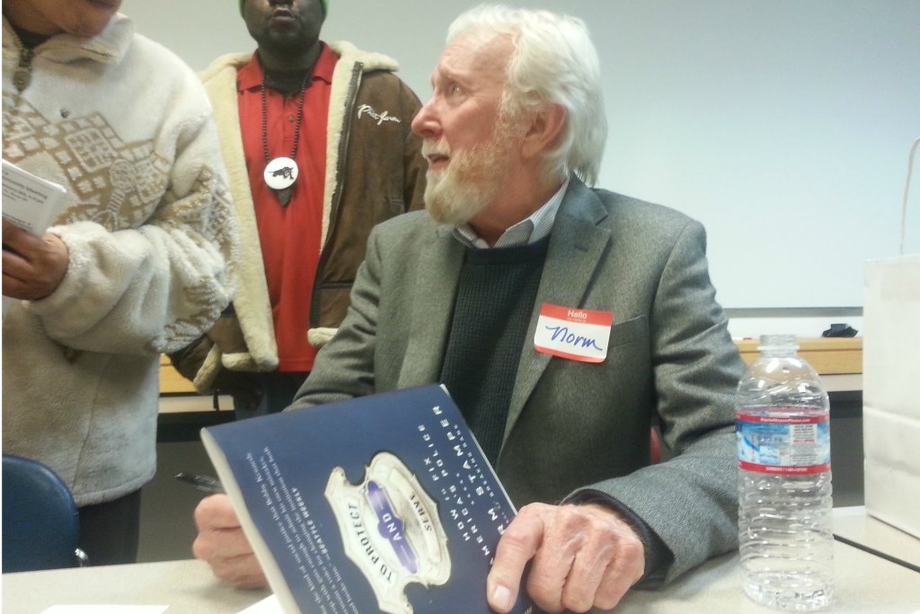 Former Seattle police chief Norm Stamper signs a copy of his book at the Not This Time meeting. Photo by Casey Jaywork.