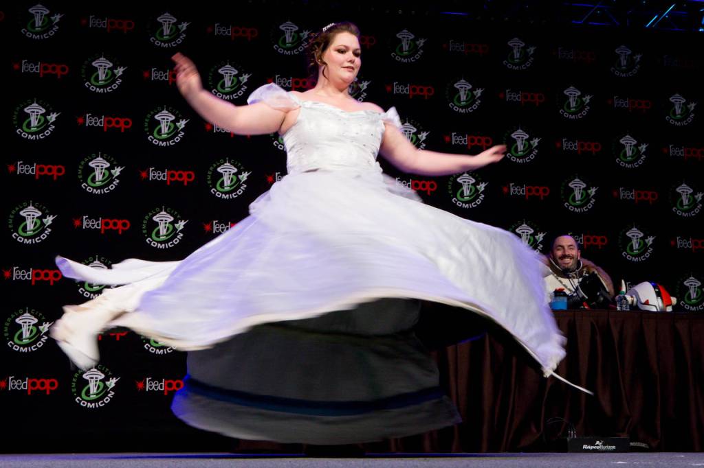 A woman dressed a Cinderella spins around to unfurl a pristine white dress underneath.