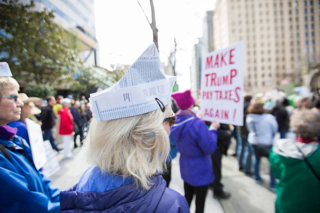 A protester wears a tax document as a hat as she waits to hear speakers at Seattle&rsquo;s Tax March.