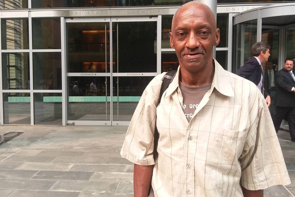 Plaintiff Reavy Washington stands in front of the U.S. District Courthouse. Behind him stands FAS staffer Chris Potter, who manages encampment evictions, while counsel for the city Matt Segal walks out from the spinning doors. Photo by Casey Jaywork
