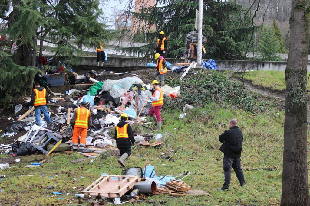 Prisoners clean up trash at &lsquo;the Field,&rsquo; an encampment that Seattle authorities destroyed, and later re-created and then re-destroyed, while Scott Lindsay was managing sweeps for Mayor Ed Murray. Photo by Casey Jaywork