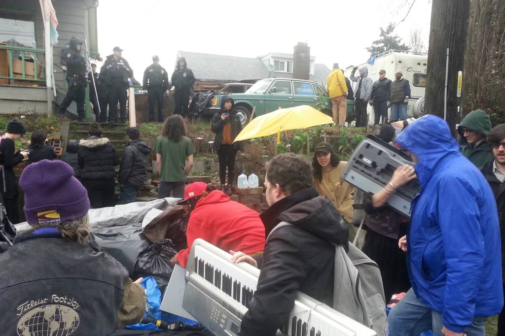 Protesters move property of the evicted Omari Tahir-Garrett out of the rain outside the Umoja PEACE Center and into two nearby garages. Photo by Casey Jaywork