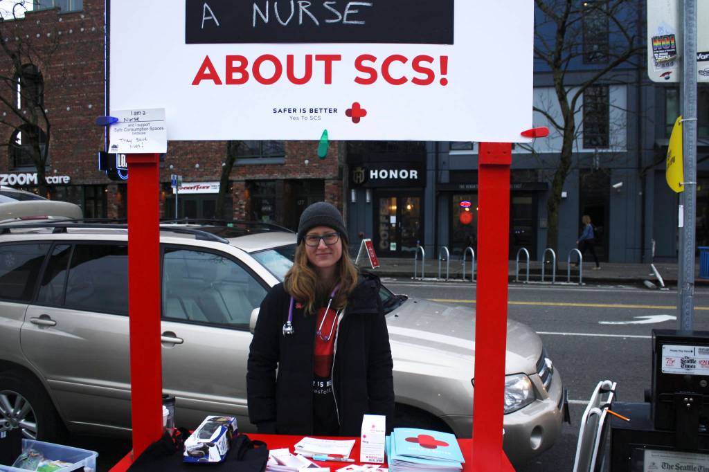 Mandy Sladky, a registered nurse, answers questions about safe consumption spaces at a public information booth outside of the Capitol Hill light rail station on February 7, 2018. Photo by Melissa Hellmann