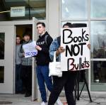 Bellevue High School student Charlie Kern holds a sign calling for more guns, less crime as another student holds a sign that reads books, not bullets. The walkout was student-led and students were able share their opinions and have a dialogue with one another. Raechel Dawson/staff photo