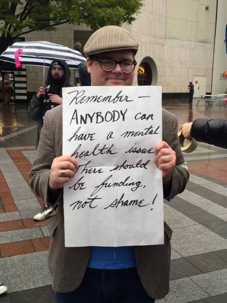 An advocate for mental health police training holds a sign at an April 14 rally at Westlake Park. Photo courtesy Brianna Kuplent/NAMI Eastside