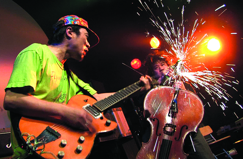 Ken Sakamoto (left) watches Hiromichi Sakamoto grind his cello.