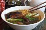 Free-range chicken broth with a leg-thigh section of braised duck, noodles, shiitake mushrooms, baby bok choy, green onions, Chinese red dates (hong zao, or jujubes), and five spice seasoning at Hue Ky Mi Gia