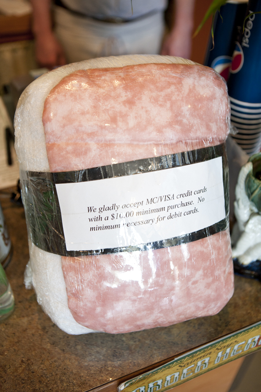 The banded pink and white cushion, which a culinary historian might slip beneath his haunches while meditating on the breathtaking adaptations and accommodations that define Pacific island cookery, now leans against the restaurant's cash register. A note directing patrons to use cash or debit cards for purchases under $10 is package taped to its midsection.
