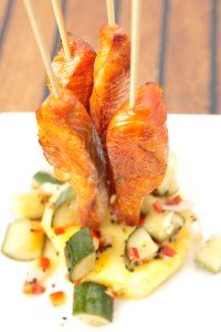 Fat skewers of smoked salmon—stood upright like sparklers in a thick wheel of pineapple, garnished with a peppery cucumber relish—make a fine starter.