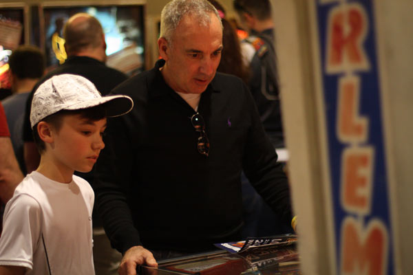 Sharing one of his favorite activities from his youth, Tom Ichelson plays pinball with his grandson, Joseph Parent. They're playing Harlem Globetrotters on Tour, a Bally game from 1979.