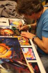 Doug Watson signs copies of some of the pinball artwork he's designed over the years.