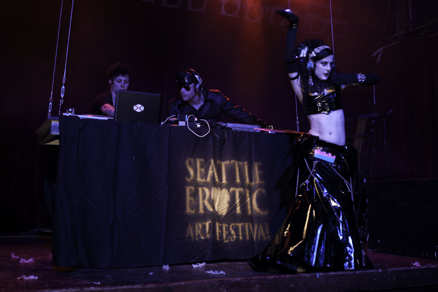 An attendee climbs on stage and shows off her intricate outfit, complete with a digital screen at her hip.