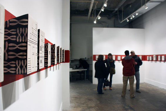 These ceramic installations line the wall on a single red strip spanning from corner to corner.