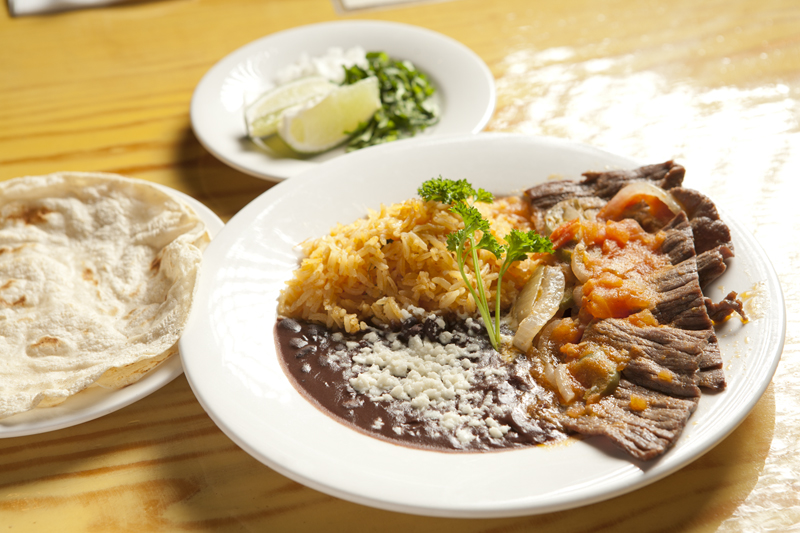 A grilled steak was nearly obscured by a heap of stewed tomatoes and onions that was lousy with natural sugars.