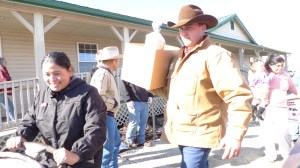 A member of the Kittitas County CattlemenaE™s Association helps a member of EllensburgaE™s Hispanic community carry a box of food to her car.