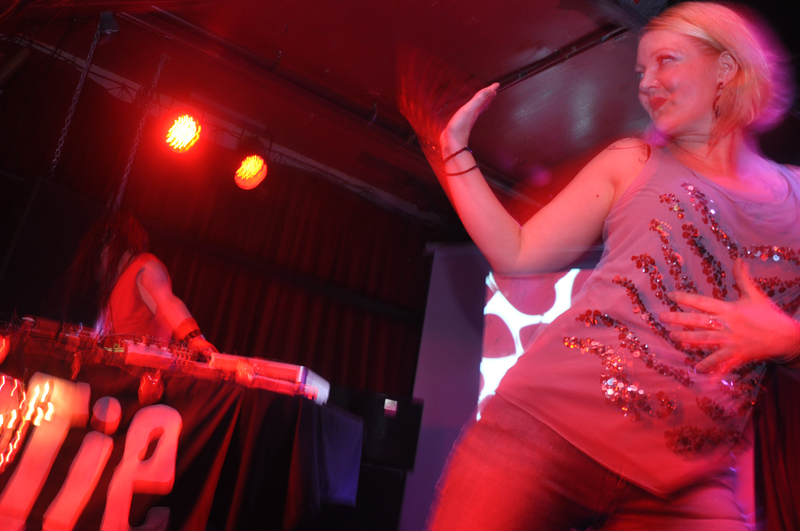 An audience member climbs on stage and dances by Adrian