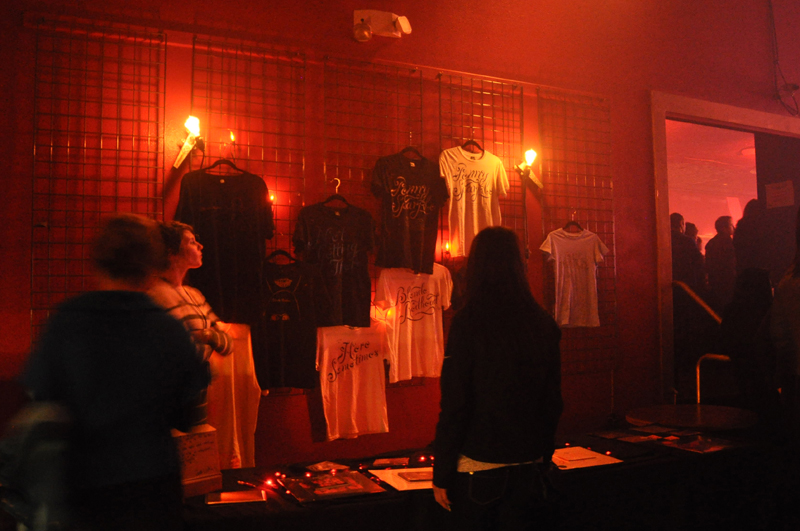 Concert-goers watch the show from the merch booth.