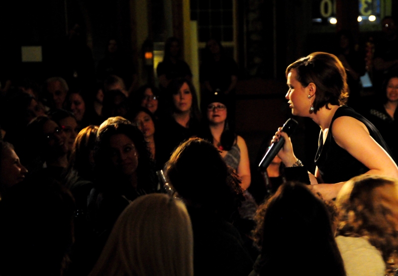 Emcee Kate Calamusa, fashion editor for Seattle Magazine, awards a prize to an engaged audience member.